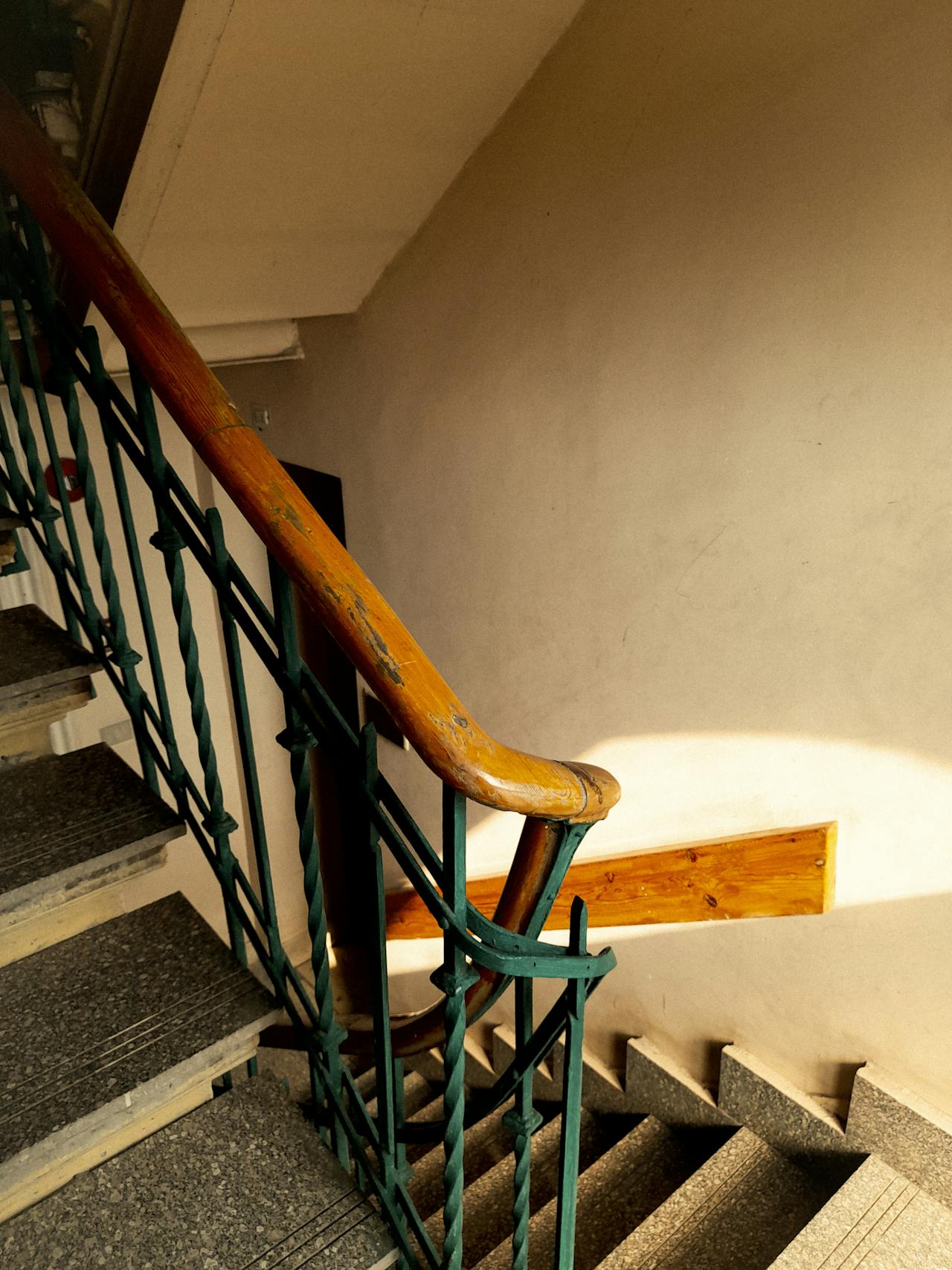 Escadaria interior de prédio com corrimão em ferro verde